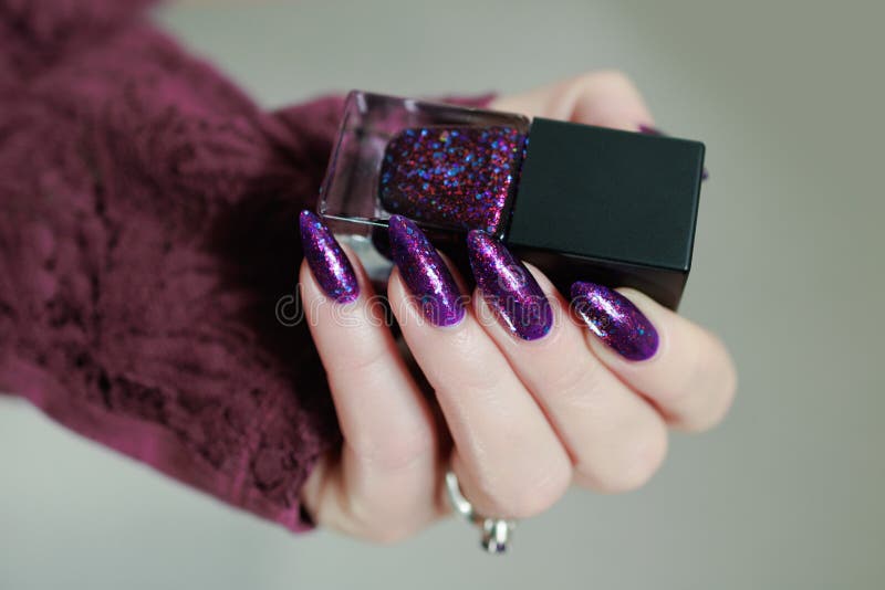 Weibliche Hand mit langen Nägeln und lila Pflaumenmaniküre stockfotos