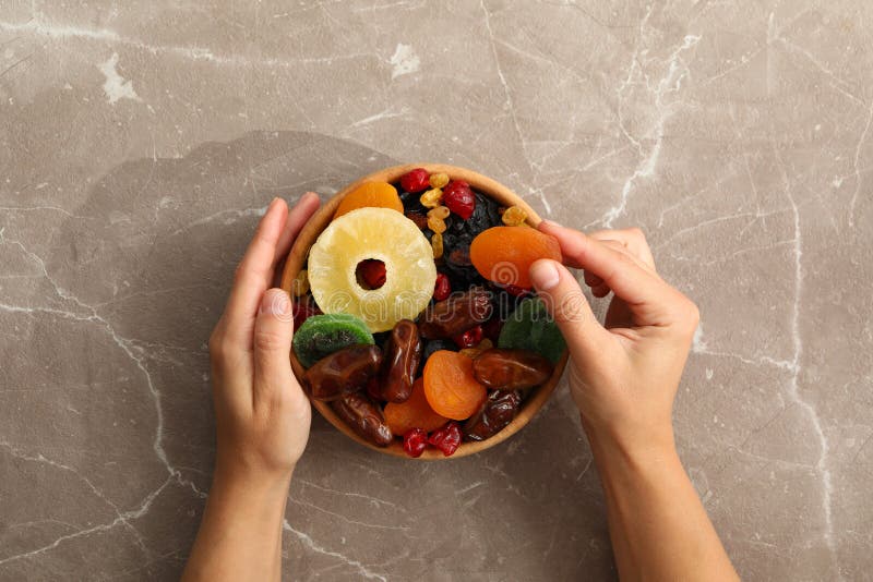 Weibliche Handgriffschüssel mit Trockenfrüchten auf grauem Hintergrund lizenzfreies stockfoto