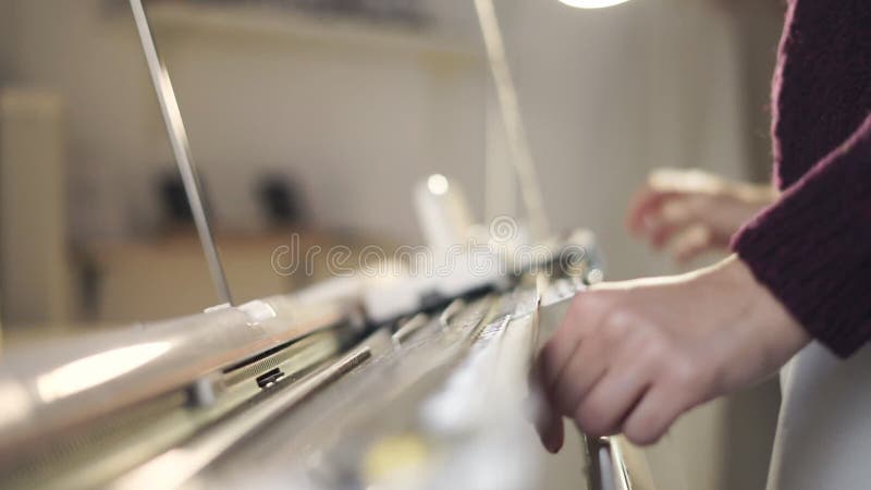 Weibliche Hände unter Verwendung der Strickmaschine für spinnendes Muster in der Werkstatt