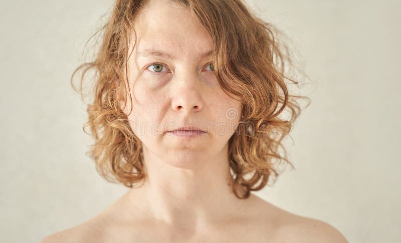 Weibliche kaukasische erwachsene Frau mit lockigen Haaren starrt direkt vor der Kamera gegen stockfoto