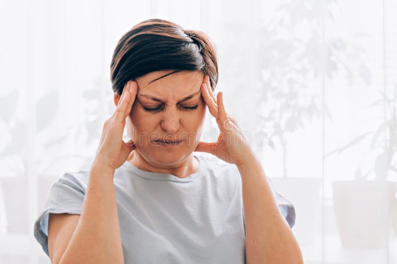 Weibliche kaukasische erwachsene Frauen, die in hellen häuslichen Umgebungen Kopfschmerzen oder Stress empfinden lizenzfreies stockfoto