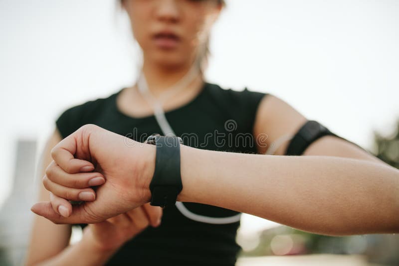 Close up shot of young sportswoman using smartwatch to track her workout performance. Fitness female monitoring her progress on smartwatch. Close up shot of young sportswoman using smartwatch to track her workout performance. Fitness female monitoring her progress on smartwatch.