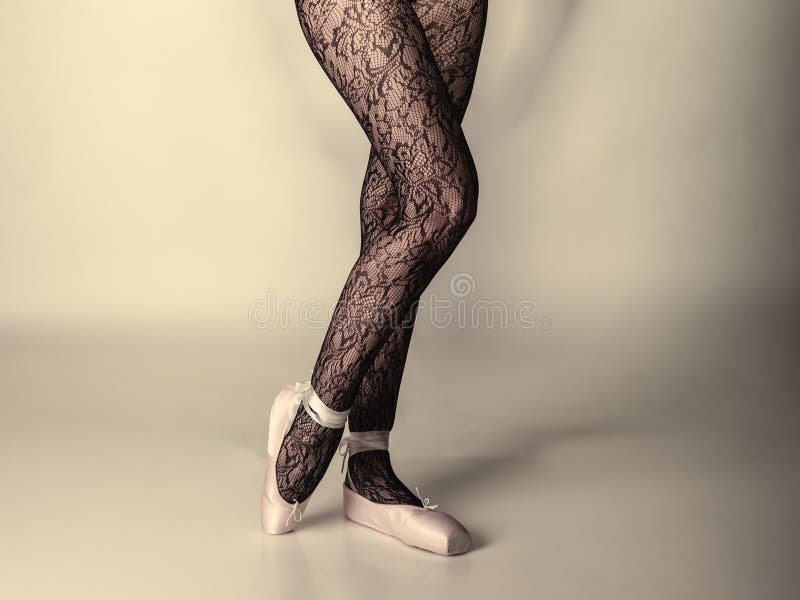 Beautiful woman ballet dancer, part of body legs in shoes and black lace tights studio shot on gray background. Beautiful woman ballet dancer, part of body legs in shoes and black lace tights studio shot on gray background