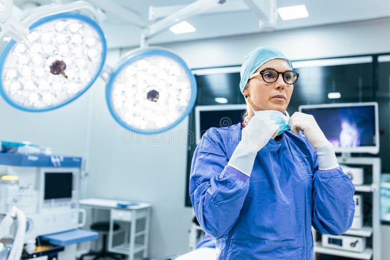 Weiblicher Chirurg mit chirurgischer Maske am Operationsraum