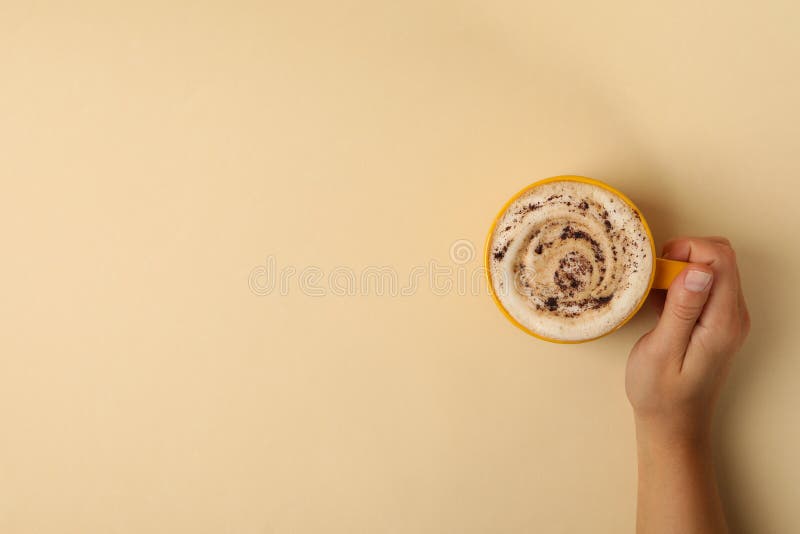 Weiblicher Handgriff-Schale Latte auf beige Hintergrund stockbild