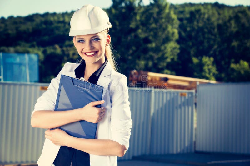 Weiblicher Ingenieur im Sturzhelm vor Baustelle lizenzfreie stockbilder Weiblicher Ingenieur im Sturzhelm vor Baustelle lizenzfreie stockbilder