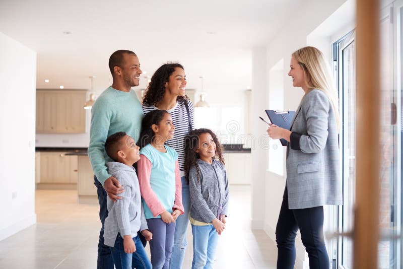 Female Realtor Showing Family Interested In Buying Around House. Female Realtor Showing Family Interested In Buying Around House