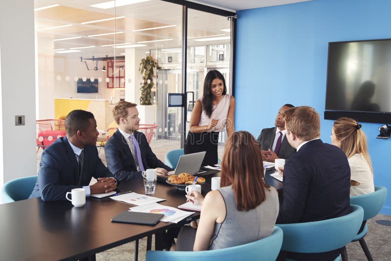 Weiblicher Manager steht, sprechend zu Kollegen im Konferenzzimmer lizenzfreies stockbild Weiblicher Manager steht, sprechend zu Kollegen im Konferenzzimmer lizenzfreies stockbild