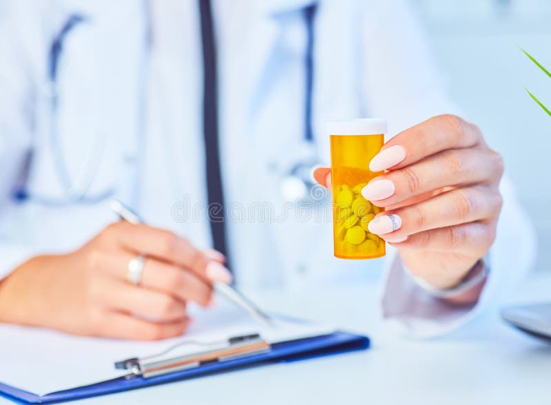 Weiblicher Medizindoktor mit Glas Pillen und schreiben dem Patienten Verordnung am Worktable Allheilmittel und Lebenabwehr lizenzfreies stockbild Weiblicher Medizindoktor mit Glas Pillen und schreiben dem Patienten Verordnung am Worktable Allheilmittel und Lebenabwehr lizenzfreies stockbild