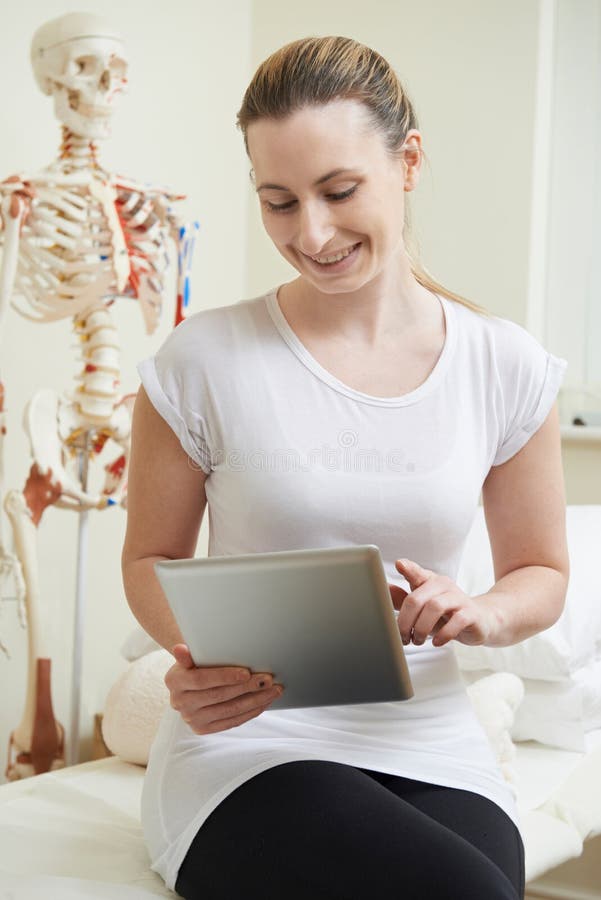 Weiblicher Osteopath in Sprechzimmer unter Verwendung Digital-Tablets lizenzfreie stockbilder Weiblicher Osteopath in Sprechzimmer unter Verwendung Digital-Tablets lizenzfreie stockbilder