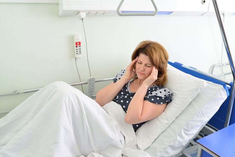 Weiblicher Patient mit Kopfschmerzen auf Bett in der Krankenstation