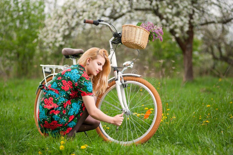 Weiblicher Radfahrer mit weißem Garten des Fahrrades der Weinlese im Frühjahr lizenzfreie stockbilder Weiblicher Radfahrer mit weißem Garten des Fahrrades der Weinlese im Frühjahr lizenzfreie stockbilder