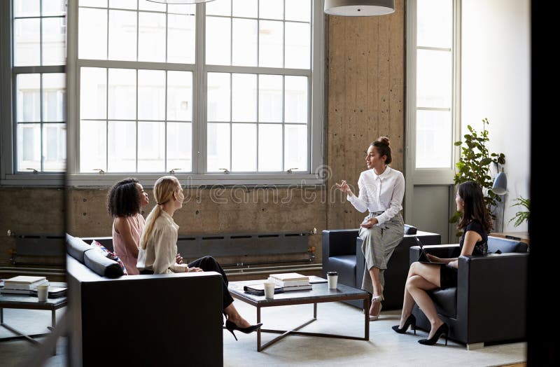 Weiblicher Sitzmanager, der mit Team bei einer informellen Sitzung spricht lizenzfreies stockbild