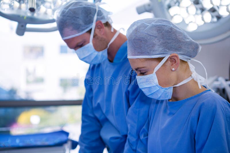 Weiblicher und männlicher Chirurg, der Theater der chirurgischen Maske in Kraft trägt