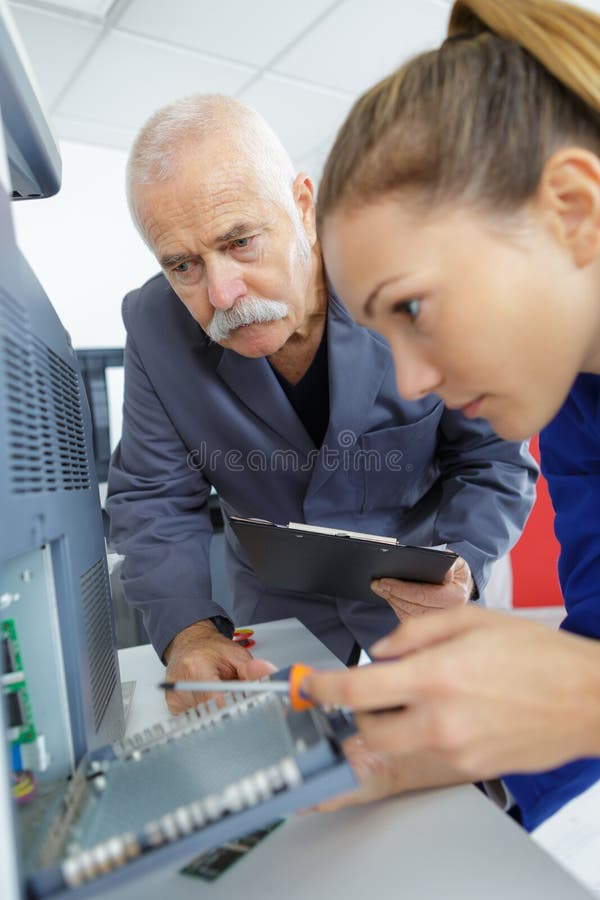 Weibliches appprentice, das Festplatte des Computers repariert lizenzfreies stockbild Weibliches appprentice, das Festplatte des Computers repariert lizenzfreies stockbild