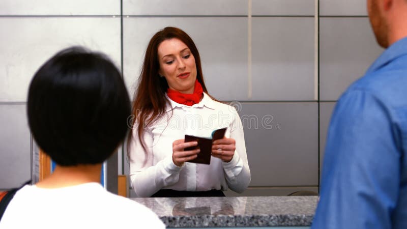 Weibliches Flughafenpersonal, das Pass überprüft und auf Pendler am Abflugschalter einwirkt