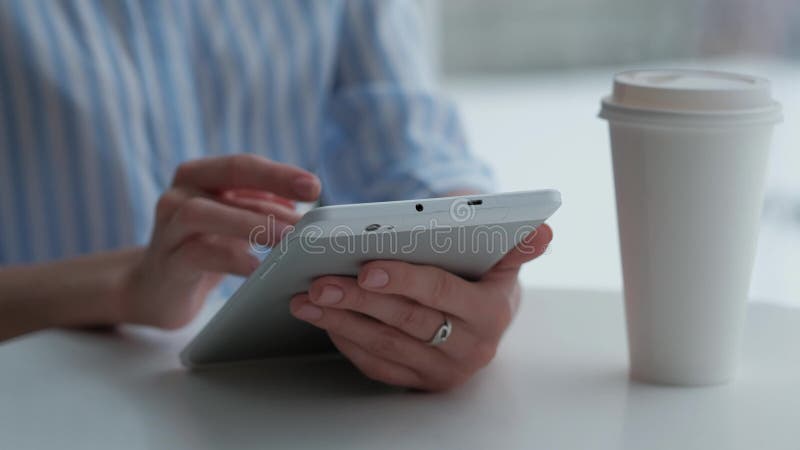 Weibliches Sitzen in der Cafeteria und Anwendung der digitalen Tablette