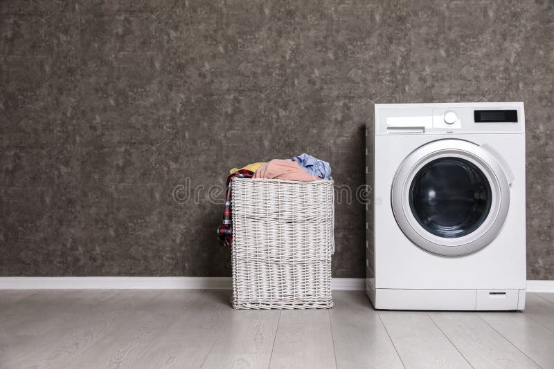 Weidenwäschekorb voll der schmutzigen Kleidung und der Waschmaschine nahe Farbwand lizenzfreie stockfotos Weidenwäschekorb voll der schmutzigen Kleidung und der Waschmaschine nahe Farbwand lizenzfreie stockfotos