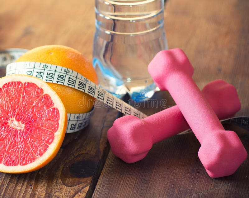 Weight loss concept. With tape measure organic grapefruit, pink dumbbells and natural bottle of water