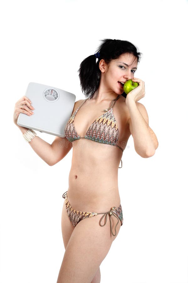 Young woman holding a scale in hand as she eats an apple. Bikini granny stock images, royalty-free photos and pictures