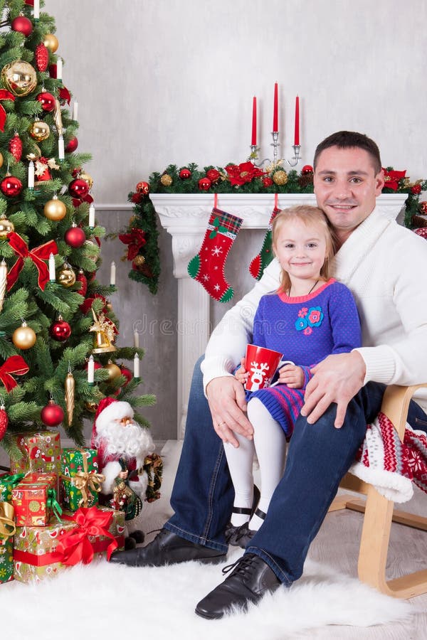 Weihnachts- oder des neuen Jahresfeier Glücklicher Vater und Tochter, die im Stuhl nahe Weihnachtsbaum mit Weihnachtsgeschenken s stockfotos Weihnachts- oder des neuen Jahresfeier Glücklicher Vater und Tochter, die im Stuhl nahe Weihnachtsbaum mit Weihnachtsgeschenken s stockfotos