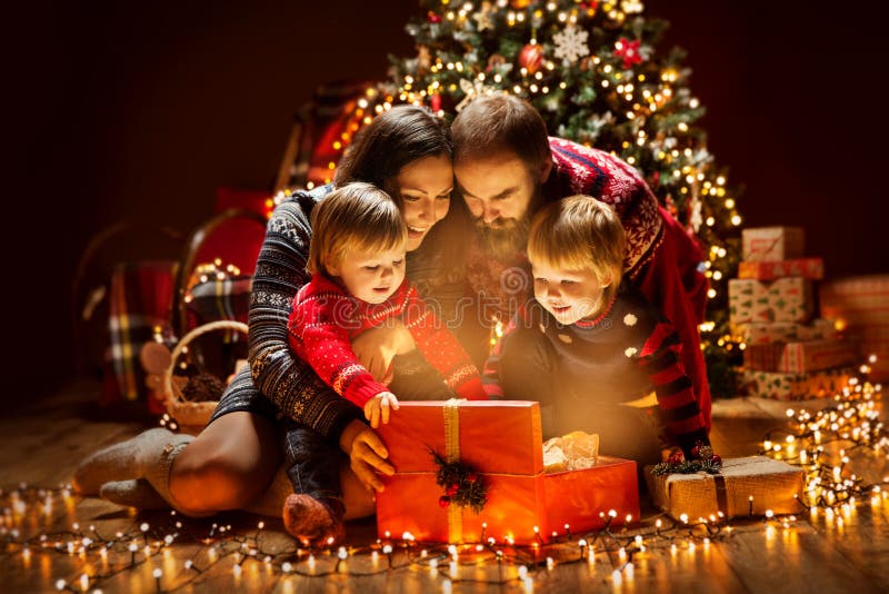 Weihnachtsfamilien-offene beleuchtende anwesende Geschenkbox unter Weihnachtsbaum, glücklicher Mutter-Vater Children lizenzfreie stockbilder