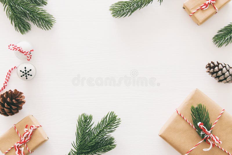 Weihnachtshintergrund mit Kiefernkegeln, -Tannenzweigen und -geschenken über hölzernem weißem Hintergrund Flache Lage, Draufsicht