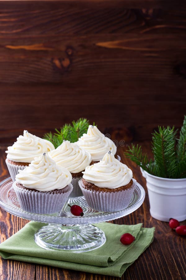 Homemade christmas cupcakes with creamcheese frosting on cake stand on wooden background with spruce twigs in ceramic pail. Homemade christmas cupcakes with creamcheese frosting on cake stand on wooden background with spruce twigs in ceramic pail