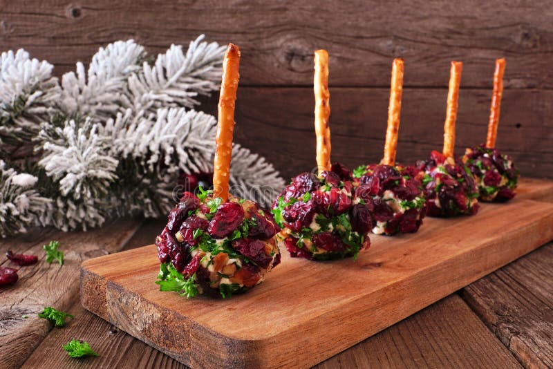 Weihnachtskuchen-Appetithäppchen mit Cranberries, Pecans und Kräutern auf einer Holzplatte gegen rustikales Holz lizenzfreies stockfoto