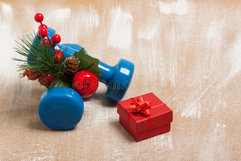Christmas sport composition with dumbbells, red gift box, red berries, green spruce on plywood background. Concept сhristmas special for healthy lifestyle and sport. Christmas sport composition with dumbbells, red gift box, red berries, green spruce on plywood background. Concept сhristmas special for healthy lifestyle and sport.