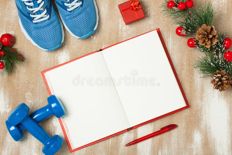 Christmas sport composition with blue sport shoes, blue dumbbells, red notebook, red small gift box, red pen and spruce branch with red berries and cones. Concept christmas special for healthy lifestyle and sport. Flat lay, horizontal orientation. Christmas sport composition with blue sport shoes, blue dumbbells, red notebook, red small gift box, red pen and spruce branch with red berries and cones. Concept christmas special for healthy lifestyle and sport. Flat lay, horizontal orientation.