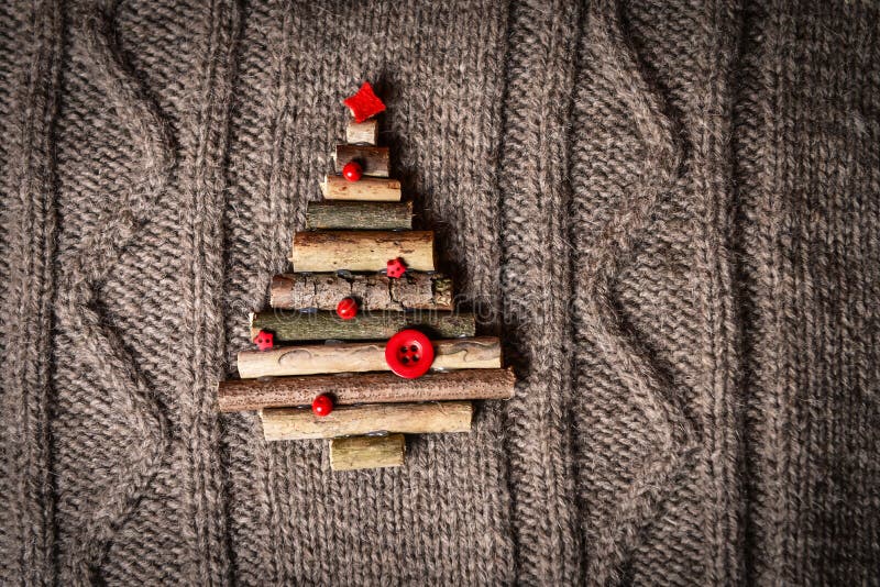 Weihnachtswarmer gestrickter Hintergrund mit den Baumdekorationen des neuen Jahres gemacht von den Stöcken Weinleseweihnachtskart