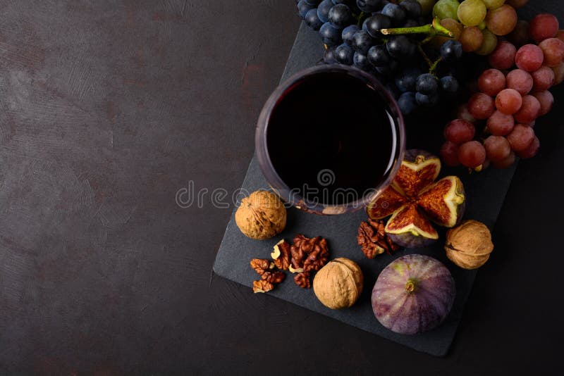 Weinglas mit dem Rotwein, Trauben, Feigen und Walnüssen, die auf dunklem hölzernem Hintergrund liegen Beschneidungspfad eingeschl lizenzfreie stockbilder Weinglas mit dem Rotwein, Trauben, Feigen und Walnüssen, die auf dunklem hölzernem Hintergrund liegen Beschneidungspfad eingeschl lizenzfreie stockbilder