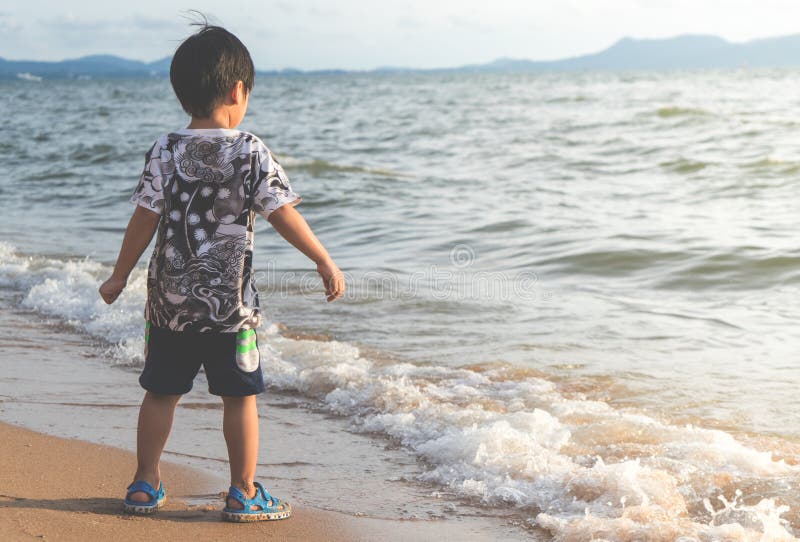 Weinig Aziatische jongen bevindt zich op het Strand royalty-vrije stock foto's Weinig Aziatische jongen bevindt zich op het Strand royalty-vrije stock foto's