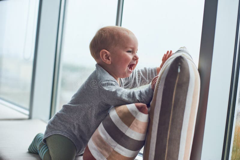 Weinig babyjongen crawlibg dichtbij groot venster op de hoofdkussens royalty-vrije stock afbeelding Weinig babyjongen crawlibg dichtbij groot venster op de hoofdkussens royalty-vrije stock afbeelding