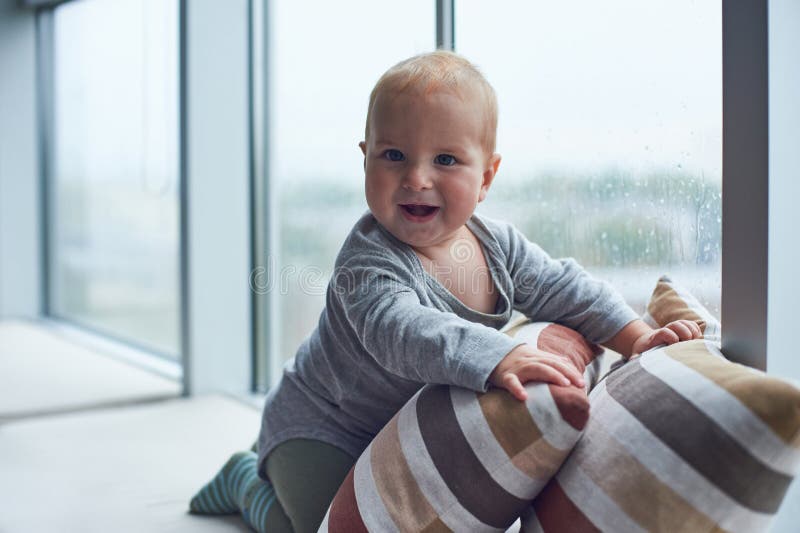 Weinig babyjongen crawlibg dichtbij groot venster op de hoofdkussens stock afbeeldingen Weinig babyjongen crawlibg dichtbij groot venster op de hoofdkussens stock afbeeldingen