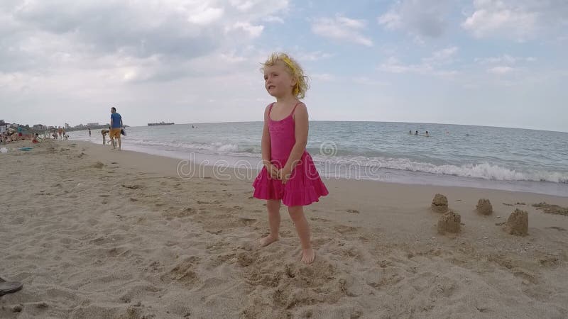 Weinig blond blauw eyed babymeisje die op de strandvideo spelen