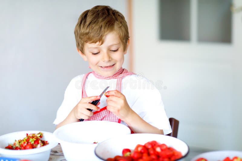 Weinig blonde jong geitjejongen die en aardbeijam in de zomer bevorderen maken stock foto's Weinig blonde jong geitjejongen die en aardbeijam in de zomer bevorderen maken stock foto's
