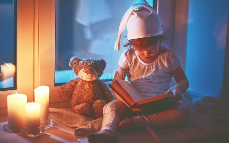 Weinig de lezingsboek van het kindmeisje door venster vóór bedtijd