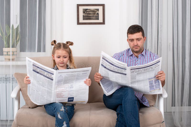 Weinig dochter en papazitting op de bank thuis en lezing de krant samen royalty-vrije stock afbeeldingen Weinig dochter en papazitting op de bank thuis en lezing de krant samen royalty-vrije stock afbeeldingen