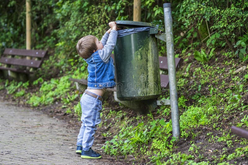 Weinig jongen die afval in de bak werpen royalty-vrije stock foto's Weinig jongen die afval in de bak werpen royalty-vrije stock foto's