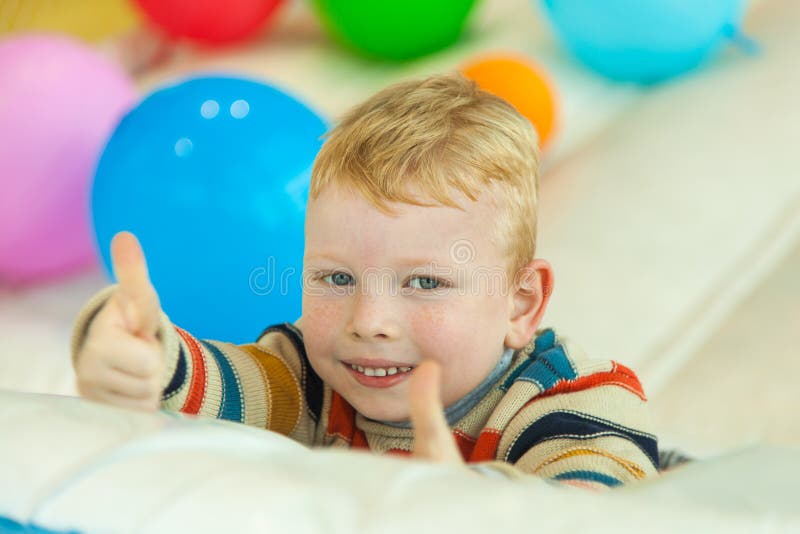 Weinig jongen die die op de vloer liggen door kleurrijke ballons wordt omringd royalty-vrije stock foto's Weinig jongen die die op de vloer liggen door kleurrijke ballons wordt omringd royalty-vrije stock foto's
