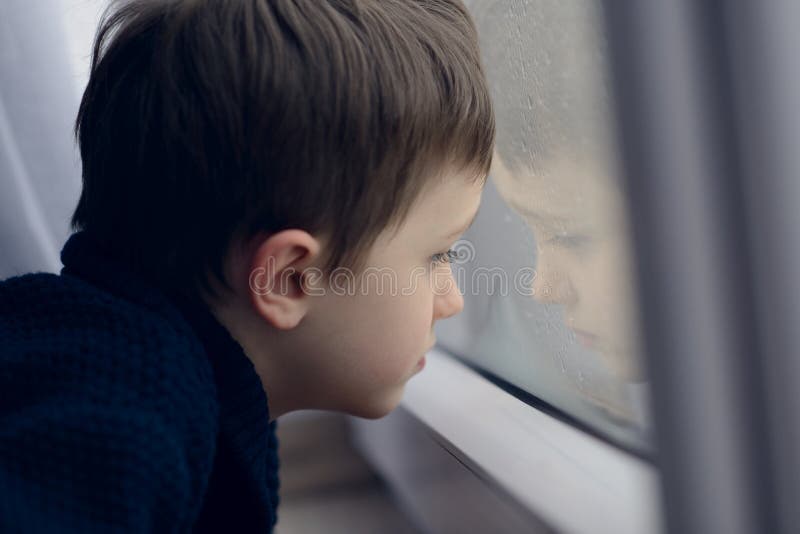 Little boy waiting by window for stop raining. Loneliness and waiting concept. Rainy day. Little boy waiting by window for stop raining. Loneliness and waiting concept. Rainy day