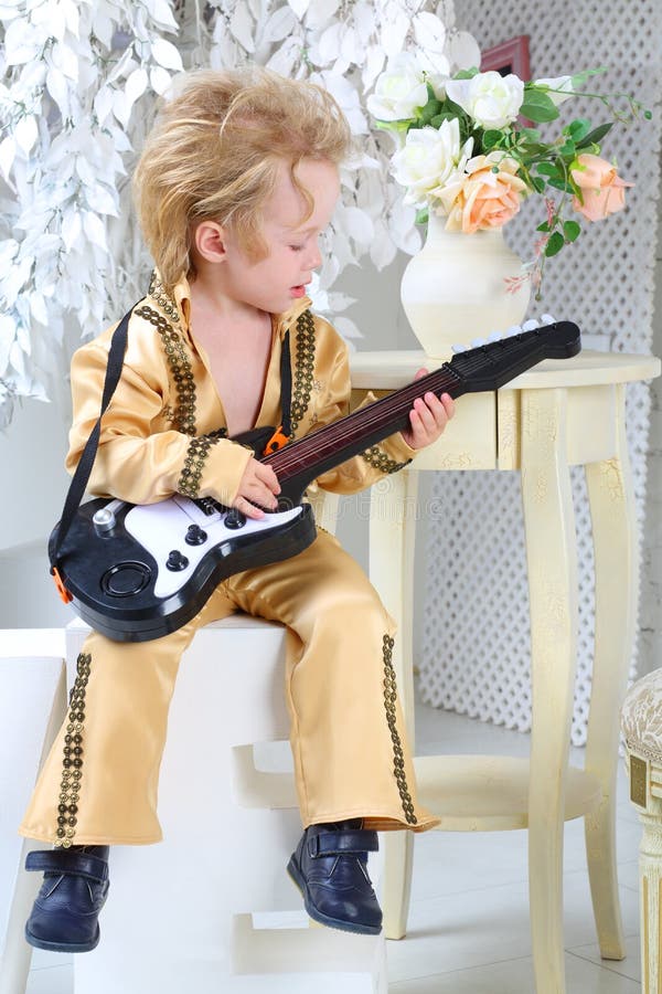 Weinig jongen die in pop retro kostuum de gitaar spelen stock foto's Weinig jongen die in pop retro kostuum de gitaar spelen stock foto's