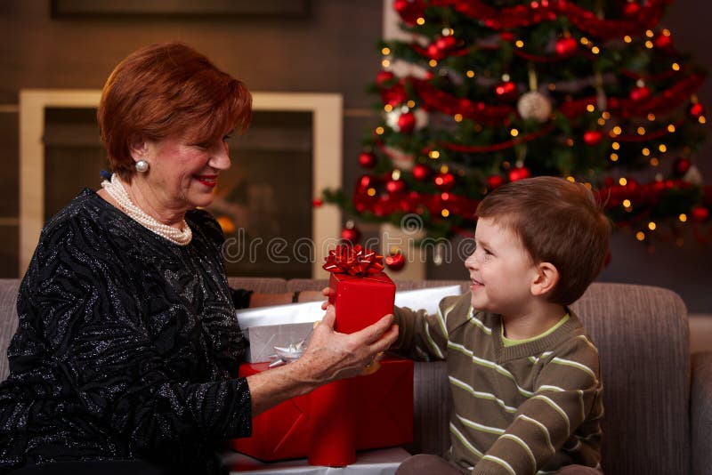 Little boy giving christmas present at christmas, smiling. Little boy giving christmas present at christmas, smiling.