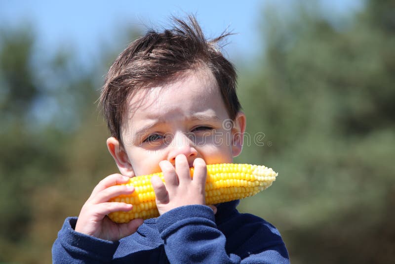 Een jongetje dat verse, gekookte mais eet royalty-vrije stock foto