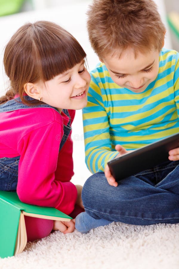 Weinig jongen en meisje die of van tablet spelen lezen royalty-vrije stock fotografie Weinig jongen en meisje die of van tablet spelen lezen royalty-vrije stock fotografie
