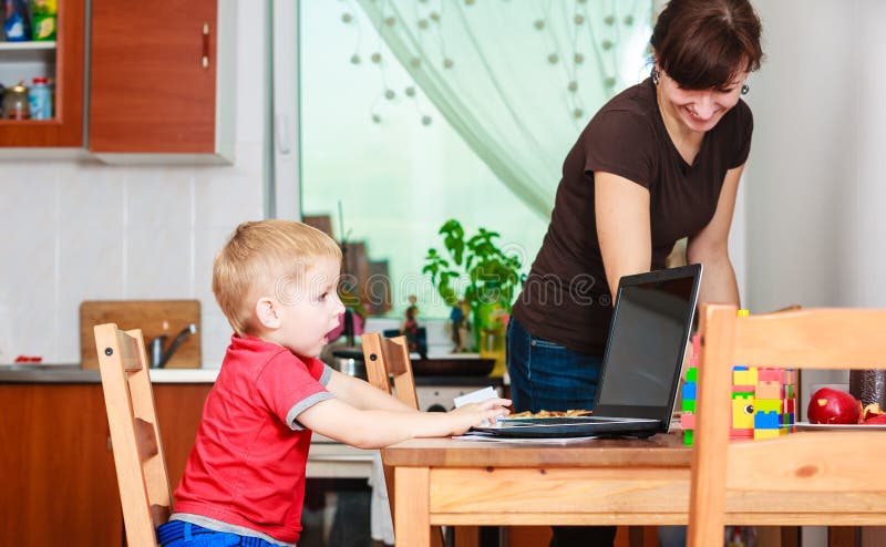 Weinig jongen met laptop en moeder het schoonmaken stock afbeeldingen Weinig jongen met laptop en moeder het schoonmaken stock afbeeldingen