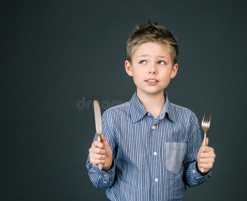 Weinig jongen met vork en mes. Hongerig kind. stock fotografie Weinig jongen met vork en mes. Hongerig kind. stock fotografie