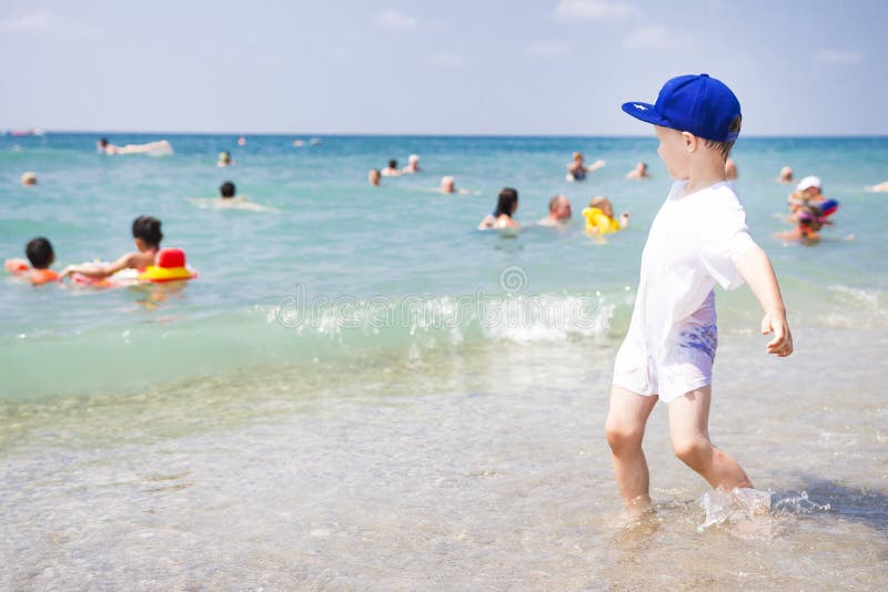 Weinig jongen speelt op overzees strand De mensen zwemmen en ontspannend in warm water van overzees Zonnig de zomerstrand op trop stock fotografie Weinig jongen speelt op overzees strand De mensen zwemmen en ontspannend in warm water van overzees Zonnig de zomerstrand op trop stock fotografie
